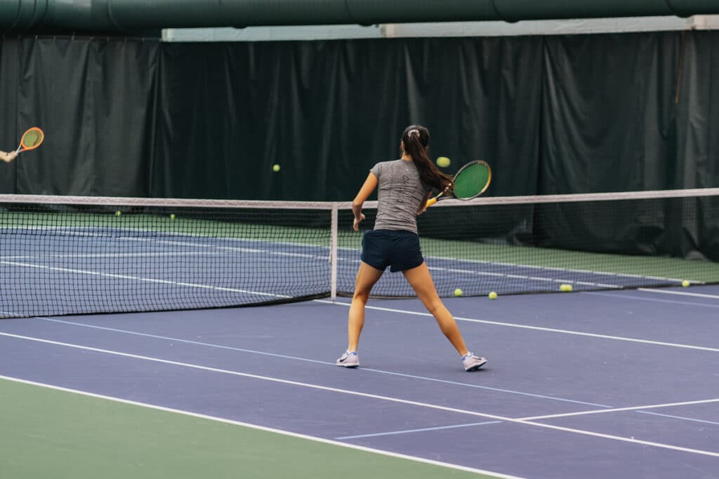 Person Playing Tennis Hitting a Ball Back with Tennis Racket