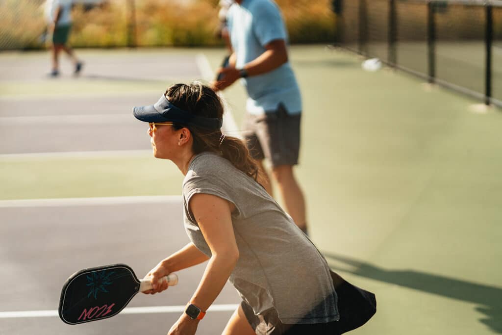 Une femme joue au pickleball sur des courts extérieurs