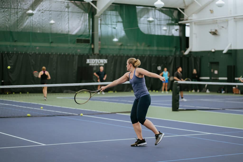 Woman prepares to hit tennis ball during Cardio Tennis class at Midtown Athletic Club