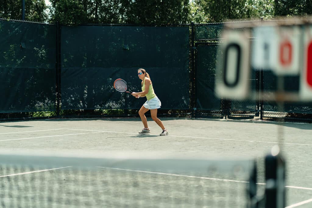 Woman plays tennis on clay court at Midtown Athletic Club Montreal