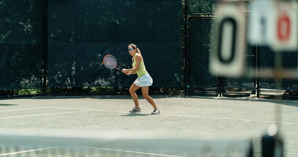 Woman plays tennis on clay court at Midtown Athletic Club Montreal