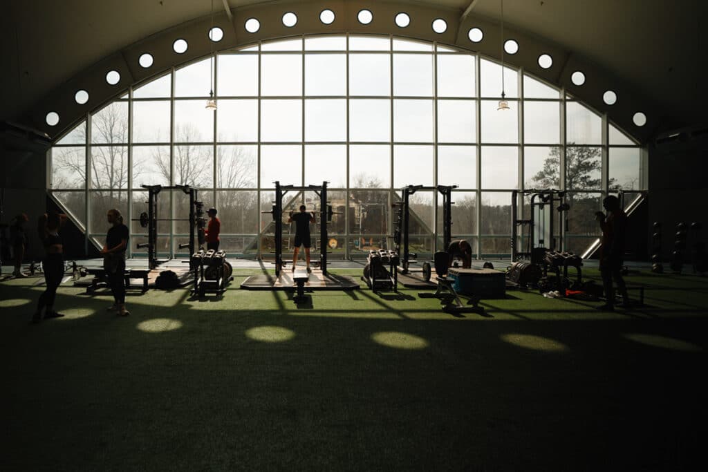 Members use weights and equipment on turf fitness floor