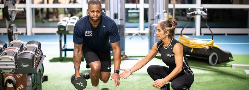 image of man lifting weights while personal trainer instructs him.