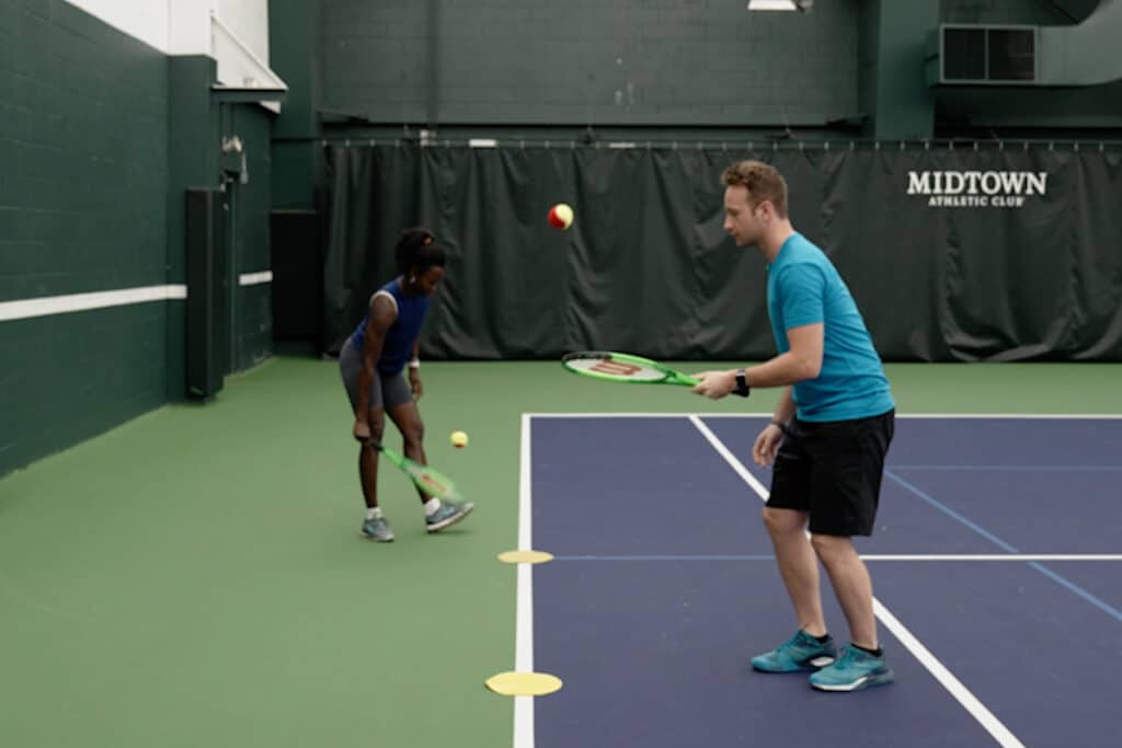 Man and woman perform tennis drills.