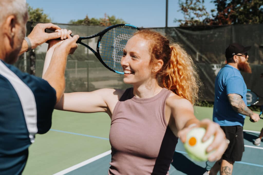 Coach helps Tennis in No Time participant with proper swing form.