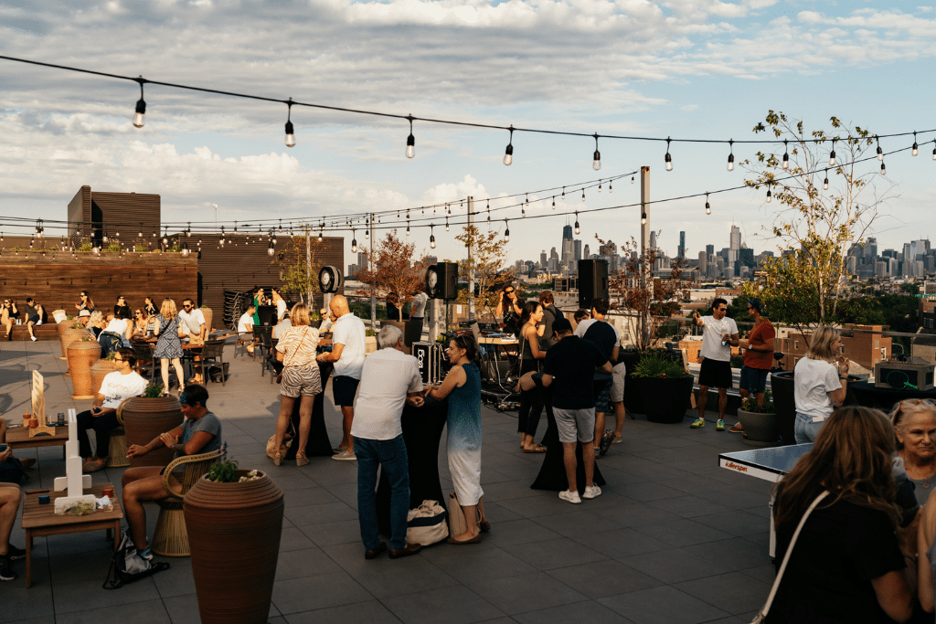A large number of guests gather on patio with the chicago skyline in the background