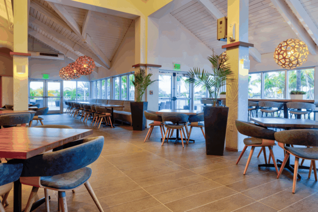 Elegant dining area at Midtown Weston featuring high ceilings, natural light, blue cushioned seating, and modern decor, offering a welcoming space for social gatherings and member dining.